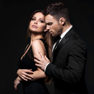 Beautiful man and woman in dark clothing on black background