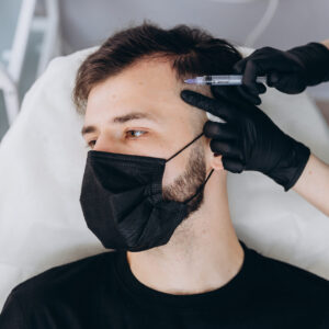 An attractive man receives mesotherapy injections to treat hair loss at the clinic. Injections into the skin and scalp