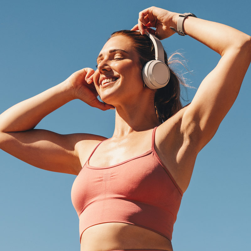 Caucasian sports woman listening to music on headphones outdoors