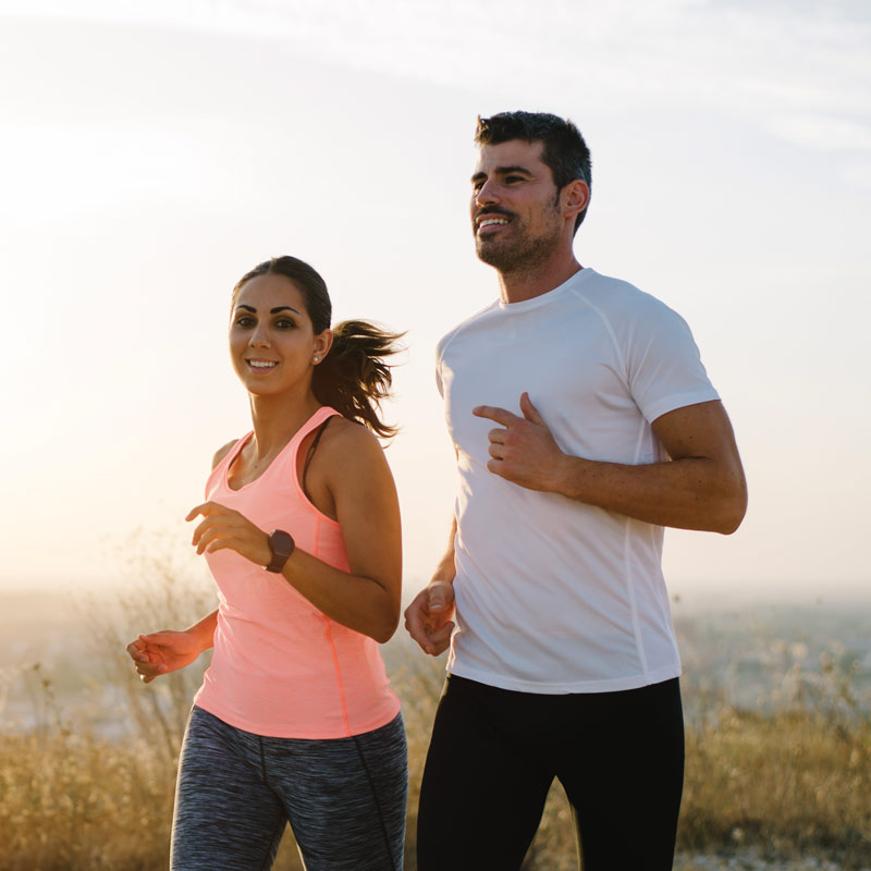Two athletes running at sunset. Man and woman training together.