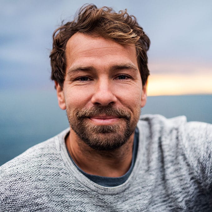 A portrait of handsome man standing outdoors, looking at camera.