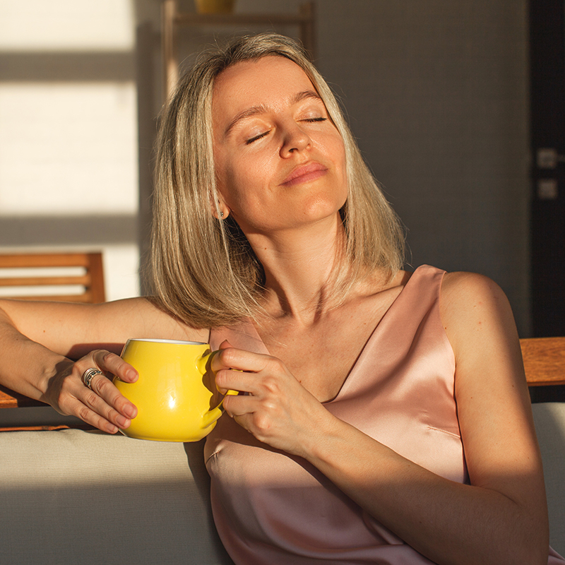 Happy dreamy middle aged woman sitting on sofa in living room wi